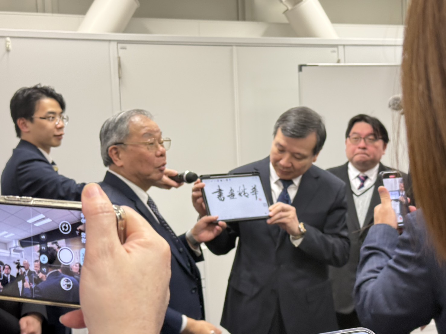 ◎驻日大使李逸洋(右)于张炳煌主任(左)讲解 e笔书法时,为其手持平板 ◎驻日大使李逸洋(右)于张炳煌主任(左)讲解 e笔书法时,为其手持平板